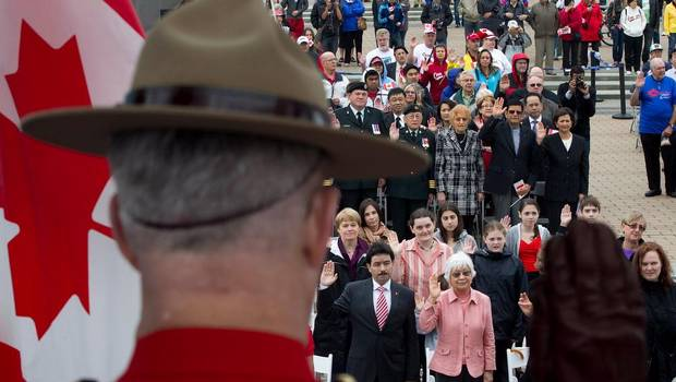 A Royal Canadian Mounted Police officer raises his hand as a group of 60 people take the oath of citizenship during a special Canada Day citizenship ceremony in Vancouver, B.C., on Sunday July 1, 2012. (DARRYL DYCK/THE CANADIAN PRESS)